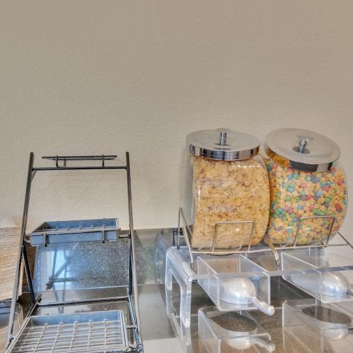 The image shows a breakfast station with cereal dispensers, napkins, and trays for food items.