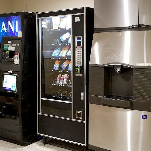 The image shows a Dasani water vending machine, a snack vending machine with visible products, and a large stainless steel ice dispenser.